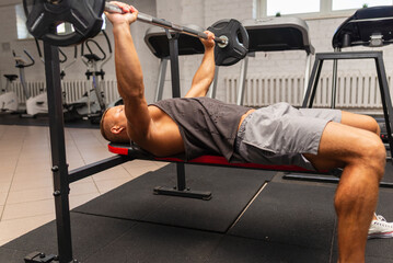 Bench Press Exercise.athletic man pumping up breast muscles on bench press at the gym.