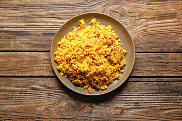 Plate with tasty pilaf on wooden background