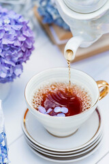 A visual for content. Still life in vintage style. A mug with a drink and hydrangea flowers on a white wooden table. The concept of a tea ceremony.