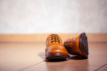 Footwear Ideas. Pair of Full Broggued Tan Leather Oxfords Broggued Shoes Against Brown Floor Tiles.
