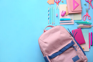 School backpack and stationery on color background