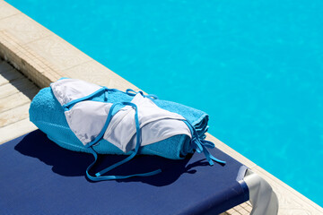 Fototapeta na wymiar Stylish swimsuit and towel on sun lounger near swimming pool