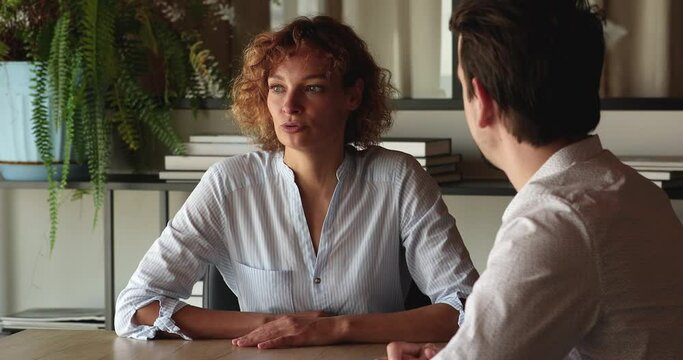 Two colleagues talking seated in office at desk, share ideas and information working on collaborative project. Business negotiations between client and manager, counselling. Job interview, hr concept