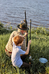 Grandfather and Grandson Going Fishing. grandfather and grandson in field near lake with fishing...