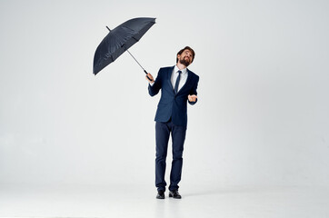 man in a suit holding an umbrella over his head protection from the rain elegant style studio