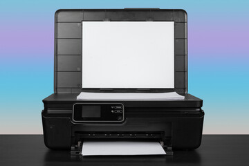 Compact laser printer on black desk against blue background