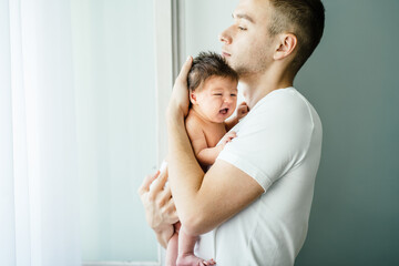 Parent love, tenderness concept. Portrait of father and son against light background, caucasian white man holding his daughter on hands. Dad embracing his baby with love and care, calming, smiling.