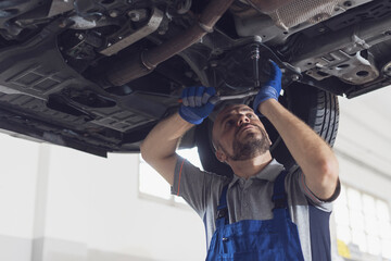 Professional mechanic working under a car