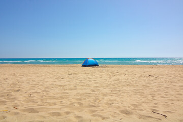 A blue tent on the beach. Camping near the sea. Camping in summer.