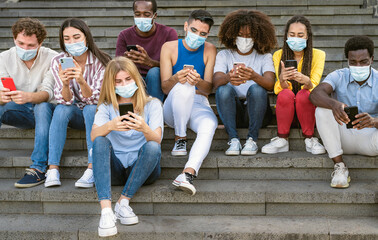 Fototapeta premium Young multiracial group of friends using mobile smartphone while wearing face mask during covid19 - Youth millennial lifestyle concept