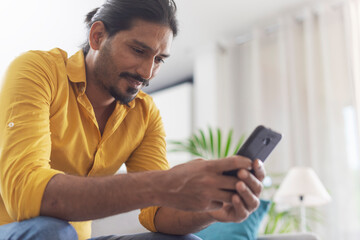 Man sitting on the couch and chatting with his smartphone