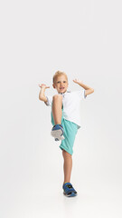 Portrait of cute preschool boy in shirt and shorts isolated on white studio background. Copyspace for ad. Childhood, education, emotion concept