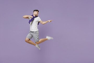 Full size body length smiling happy young brunet man 20s wear white t-shirt purple shirt jump pointing back on workspace area copy space mock up isolated on pastel violet background studio portrait