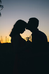 A couple of lovers at sunset. Only shadows and silhouettes are visible. Romantic look and place for text. Golden rays and black silhouettes create aesthetics and romance.