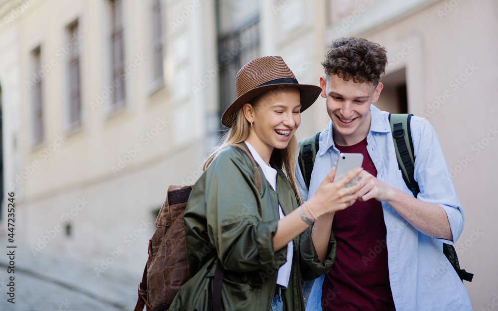 Wall mural Young couple travelers with smartphone in city on holiday, sightseeing.