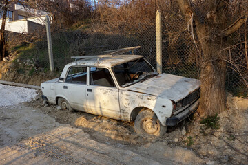 Obraz na płótnie Canvas Old broken down soviet-style car by a tree