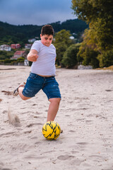 Niño en la playa jugando al futbol con un balón amarillo en la playa © Mac Estudio