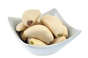 Gousses d'ail dans un ramequin en gros plan sur fond blanc