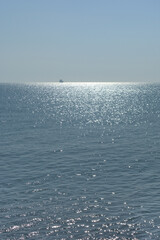 Calm sea, clear sky and morning sun with a ship on the horizon