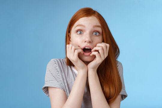 Shocked Speechless Gasping Young Redhead Girl Staring Impressed Stunned Watching Important Moment Tv Series Biting Fingers Open Mouth Shook Standing Excited Blue Background Anticipating