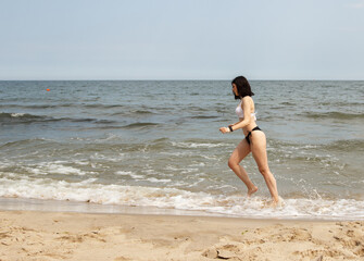 young beautiful girl running along the sand of the sea shore