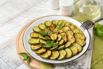 Homemade roasted young zucchini. Wooden white surface, copy space.