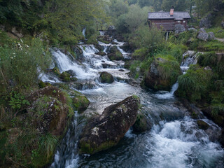 Small traditional wooden water mill by the wild river Krupa with big rocks and cascades on popular...
