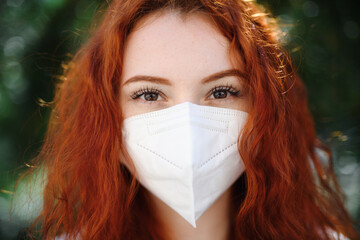 Close-up portrait of young woman with respirator looking at camera outdoors in city, coronavirus concept. - obrazy, fototapety, plakaty