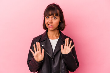 Young mixed race woman isolated on pink background rejecting someone showing a gesture of disgust.