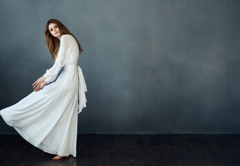 Fototapeta na wymiar elegant woman in white dress dark background posing performance