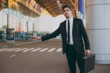 Bottom view young traveler businessman man 20s in black classic tie suit stand outside at...