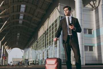 Bottom view traveler businessman young man 20s in black suit stand outside at international airport...