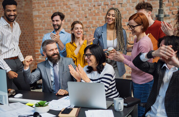 Group of excited entrepreneurs working on project indoors in office, celebrating successful...