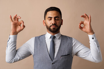 Arab businessman standing in zen pose meditating against beige background