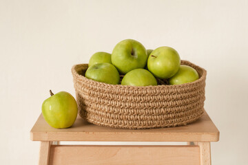 Ripe green apples in a handmade jute basket. Minimalistic home design. Cozy modern natural interior details.