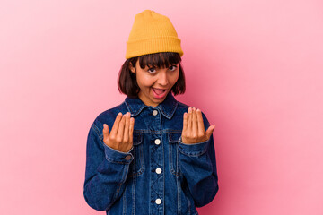 Young mixed race woman isolated on pink background pointing with finger at you as if inviting come closer.