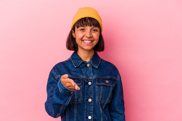 Young mixed race woman isolated on pink background stretching hand at camera in greeting gesture.