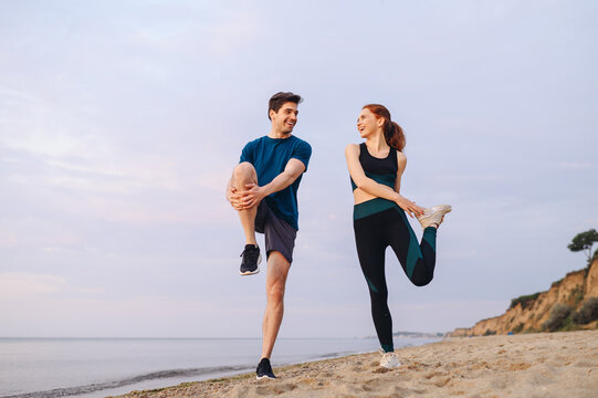 Full body couple young two friends sporty sportswoman sportsman woman man in sport clothes warm up training run do exercise on sand sea ocean beach outdoor jog on seaside in summer day cloudy morning.