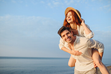 Young smiling happy couple two friends family man woman in white clothes boyfriend give piggyback...