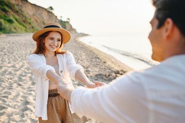 Young smiling fun couple two friends family man woman in white shirt clothes whirling by hands walk...