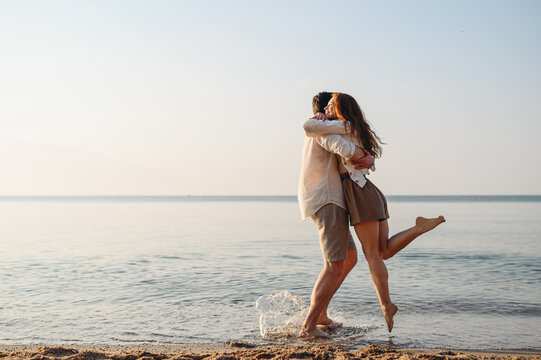 Side view happy smiling young couple two family man woman in white clothes hug boyfriend hold girl rest meeting together at sunrise over sea beach ocean outdoor seaside in summer day sunset evening