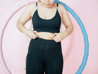 Lose belly fat concept from close up woman in sportswear with hand holding her own belly fat and cellulite.