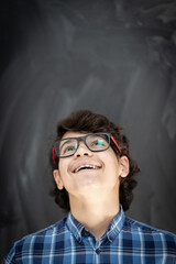 Teenage boy with glasses in front of classroom chalkboard