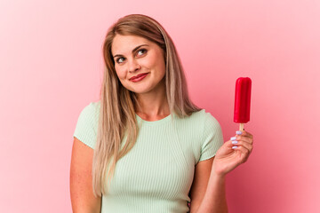 Young russian woman holding an ice cream isolated on pink background dreaming of achieving goals...