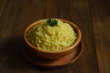 a bowl of  yellow rice on a wooden table 