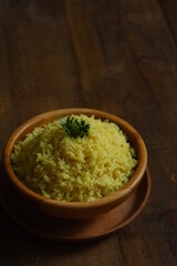 a bowl of  yellow rice on a wooden table 