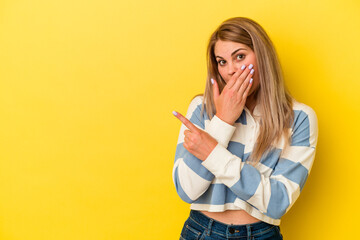 Young russian woman isolated on yellow background pointing to the side