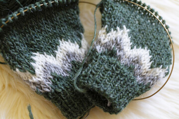 Green, gray and white Icelandic wool knitting sleeves for kids sweater with needles in progress
