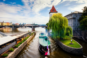Prague view of the city canal with pleasure boat. An ancient watchtower. Vltava river. Prague,...