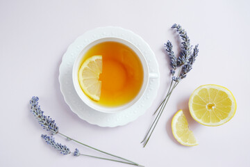 White teacup of tea with lemon, dry lavender on the light purple background. Composition in harmony...